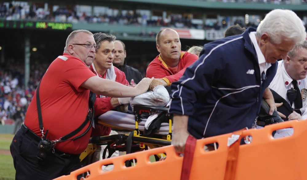 Boston Red Sox medical personnel tend to a woman, who was hit by a wooden shard off a broken bat of Oakland Athletics’ Brett Lawrie, at Fenway Park in Boston on Friday.