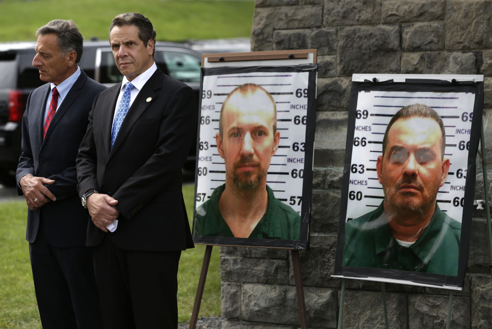 Vermont Gov. Peter Shumlin, left, and New York Gov. Andrew Cuomo listen during a news conference in front of the Clinton Correctional Facility in Dannemora, N.Y., on Wednesday. The large photos show fugitives David Sweat and Richard Matt, two killers who escaped using power tools.