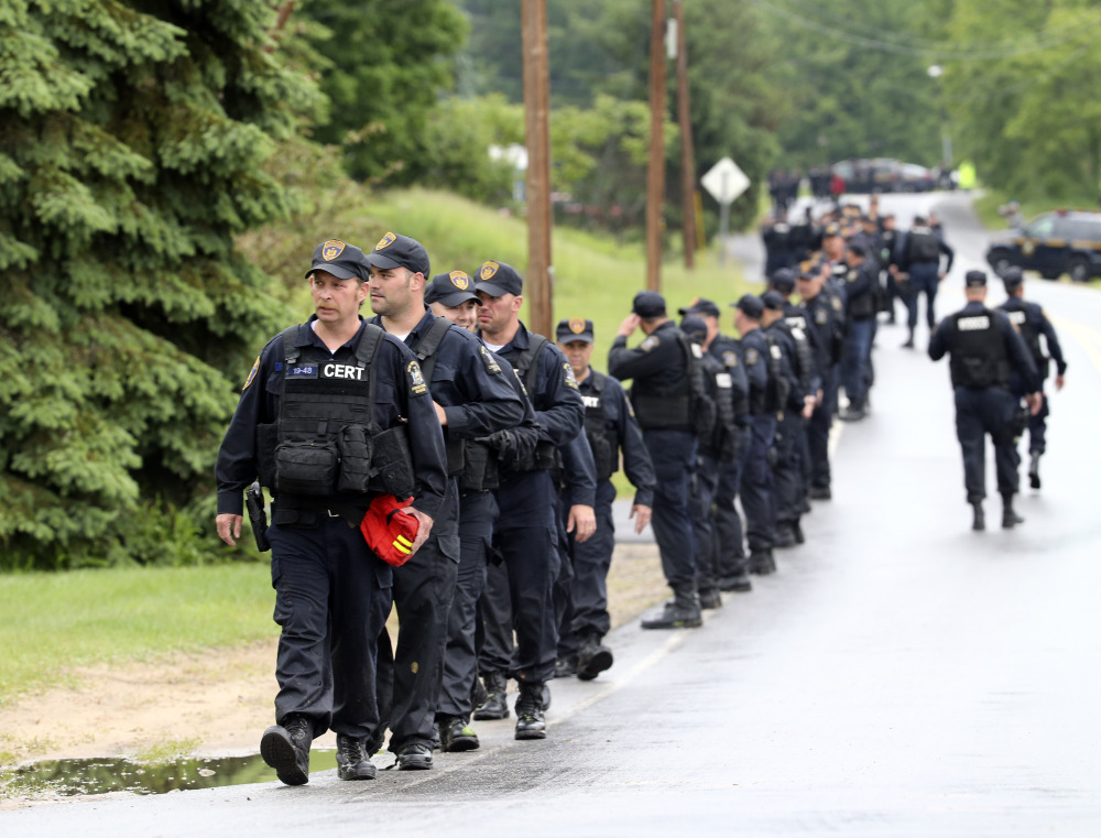 Law enforcement officers walk along Trudeau Road at Route 3 after emerging from the woods during a search for two escapees from Clinton Correctional Facility on Friday, June 12, 2015, near Dannemora, N.Y. Squads of law enforcement officers are searching for David Sweat and Richard Matt, two murderers who escaped from the maximum-security prison in northern New York. (AP Photo/Mike Groll)