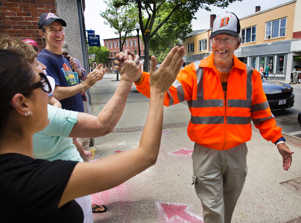 Ray Shevenell, 74, gets high-fives from supporters as he completes his 188-mile walk Friday. He retraced the steps from Quebec to Biddeford that his great-great-grandfather, Israel Shevenell, made in search of work in 1845.