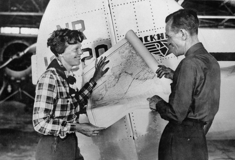Aviator Amelia Earhart, left, and navigator Fred Noonan pose with a map of the Pacific Ocean showing the planned route of the round-the-world flight during which they and their plane went missing.