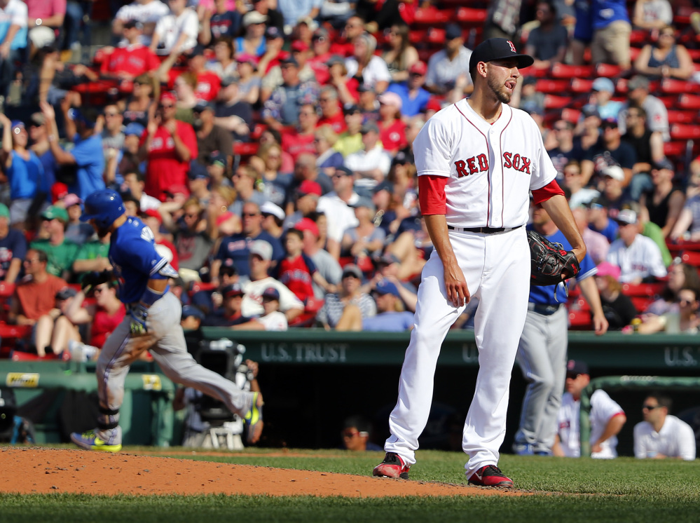 Boston Red Sox relief pitcher Matt Barnes stands on the mound after giving up the winning home run to Toronto Blue Jays’ Russell Martin, left, in the 11th inning Saturday at Fenway Park.