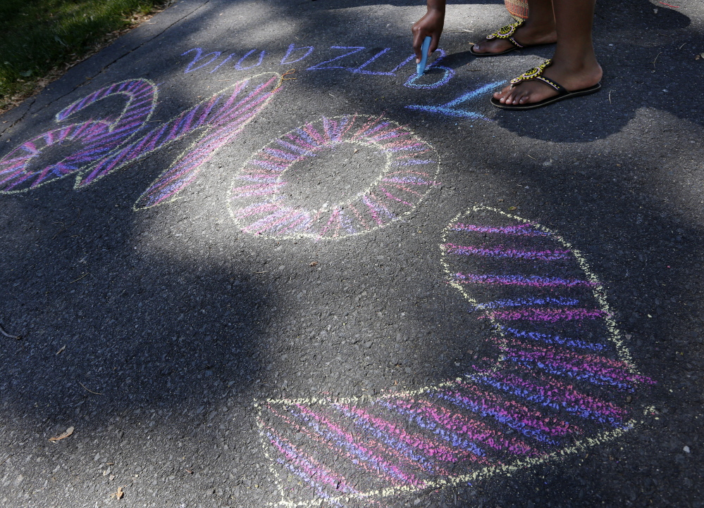 Deborah Mrema, 18, of Portland, originally from Tanzania, draws with chalk on the sidewalk.