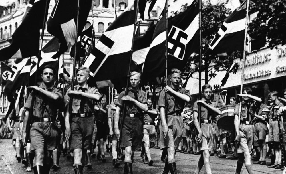 Boys march beneath Nazi standards in Berlin in 1936. Anti-Semitic propaganda had a lifelong effect on German children schooled during the Nazi period, leaving them far more likely to hold racist views than those born earlier and later.
