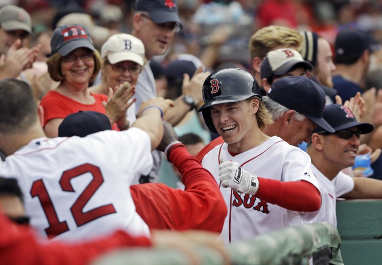 Boston’s Brock Holt celebrates in the dugout after hitting a solo home run in the seventh inning of Tuesday’s game against the Atlanta Braves. Holt later tripled to complete the cycle.
