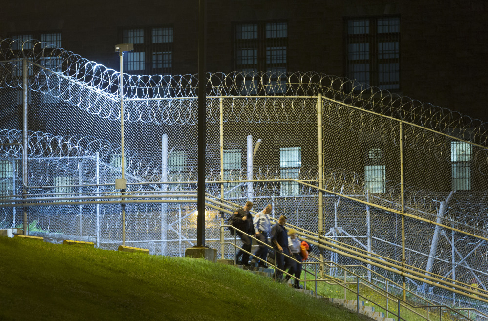 Corrections officers walk next to a fence covered in razor wire as they leave work at the Clinton Correctional Facility, Monday, in Dannemora, N.Y.