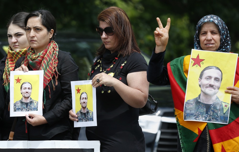 Members of  the New England Kurdish Association hold pictures of Keith Broomfield outside the Grace Baptist Church in Hudson, Mass., after his funeral service Wednesday.
