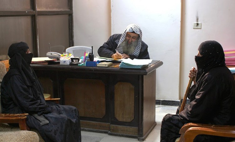 In this photo released on Feb. 10 by a militant website, two women sit in the office of an Islamic State group judge, center, at an Islamic court in al-Tabqa town in Raqqa City, Syria.