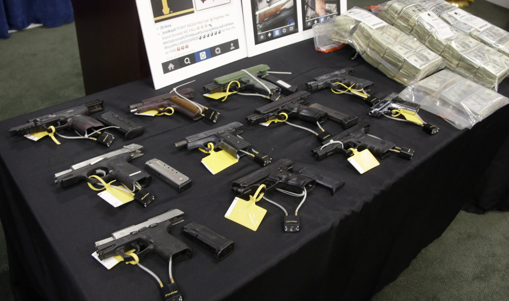 Weapons and money collected during a gang roundup are displayed at a news conference Thursday in Boston.