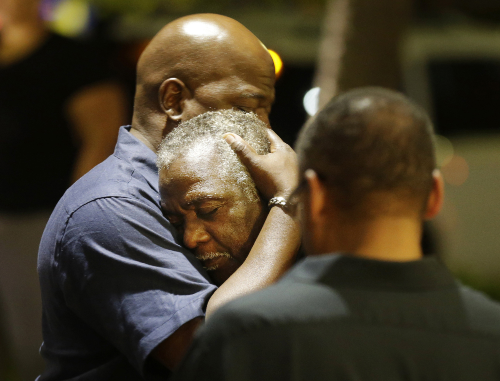 Worshippers embrace after a group prayer across the street from the scene of a shooting Wednesday night at Emanuel AME Church in Charleston, S.C. A white man opened fire during a prayer meeting inside the historic black church, killing nine people, including the pastor and three other clergy members, in an assault that authorities described as a hate crime.