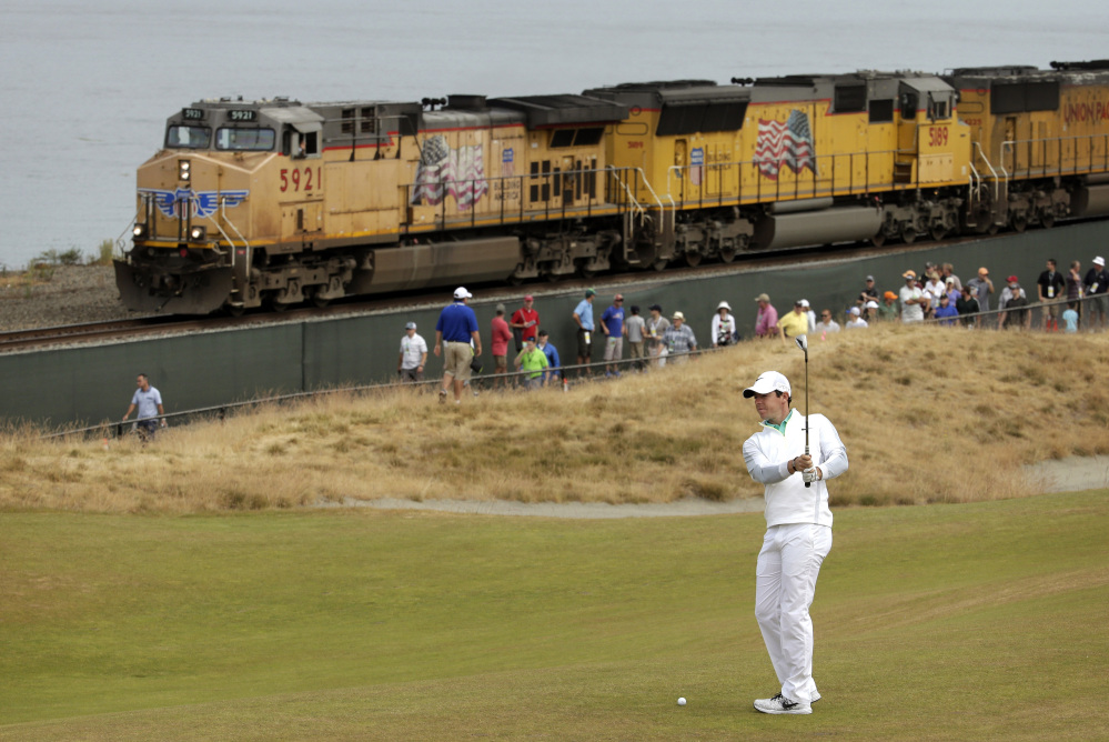Rory McIlroy of Northern Ireland prepares to hit from the 16th fairway as a fright train rolls past during the first round of the U.S. Open golf tournament at Chambers Bay on Thursday in University Place, Wash.