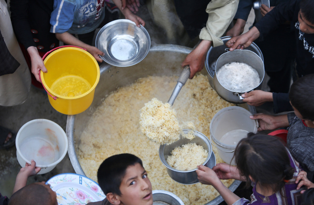 Afghan villagers hold out their plates for food donated by other villagers as they prepare to break their fast during the holy month of Ramadan in Kabul, Afghanistan, on Friday.
