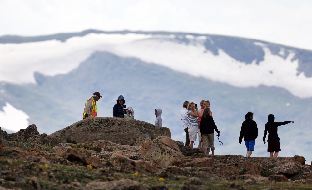 Volunteer Tundra Guardian Rick Beesley, far left, talks with visitors at a scenic overlook in Rocky Mountain National Park in Colorado. Researchers are tracking volunteers to document how visitors use National Parks and learn about their impact on park ecosystems.