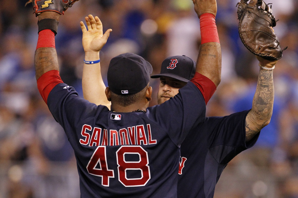 Boston’s Mike Napoli celebrates with Pablo Sandoval at the end of Friday night’s 7-3 win against the Kansas City Royals. Napoli drove in two runs with a single, and Sandoval doubled and singled.