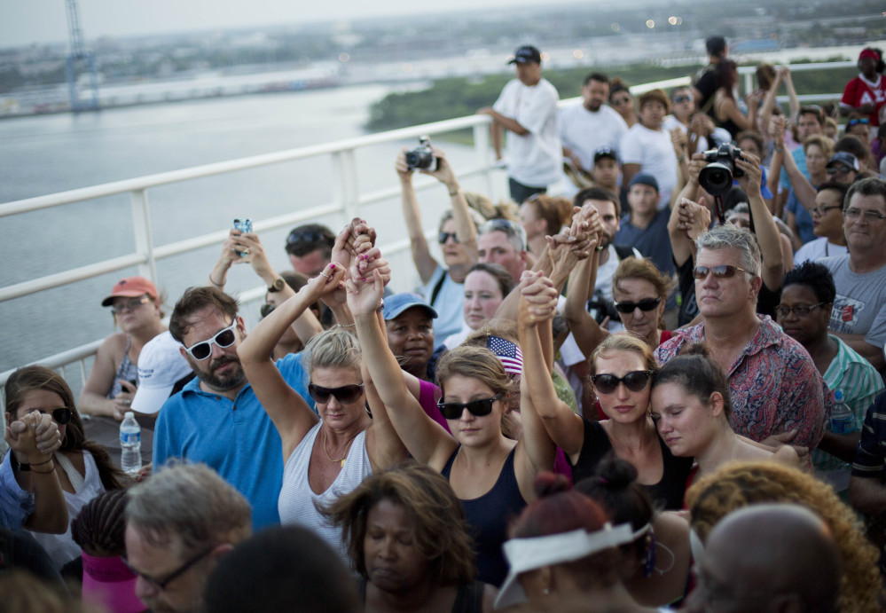 People join hands in a moment of silence as thousands of marchers meet on Charleston’s main bridge Sunday evening in solidarity after the shooting deaths of nine black people last Wednesday allegedly by a self-described racist.