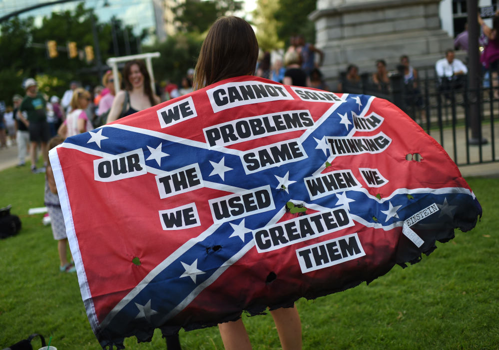 A protester holds a burned Confederate flag during a Columbia, S.C., rally Saturday, urging South Carolina officials to remove the Confederate battle flag from the Statehouse grounds. On Monday, the state’s governor, Nikki Haley, joined in the call to take down the banner.