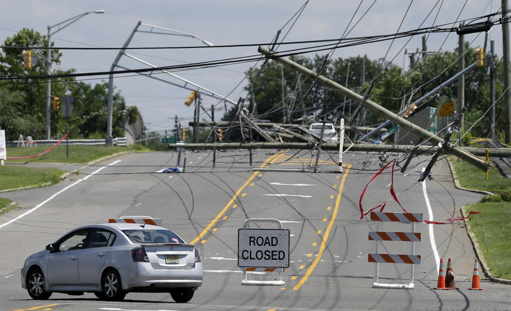 A driver turns her car at a closed road Wednesday after a violent storm downed poles and power lines Tuesday night in Gibbstown, N.J. Many were without power Wednesday.
