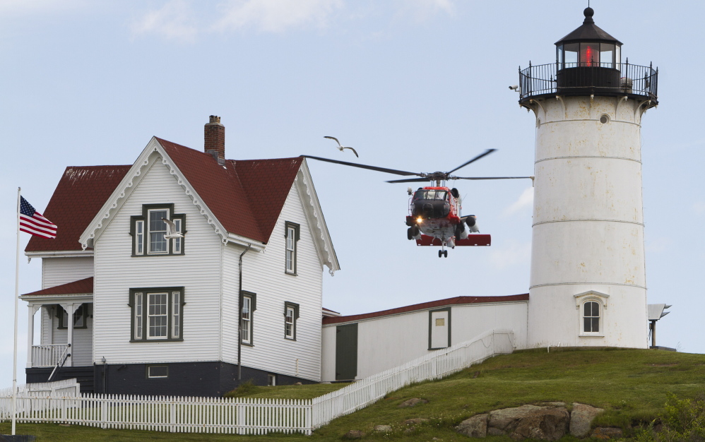 A U.S. Coast Guard helicopter hovers over Nubble Light as it searches for a missing person in the waters off Cape Neddick on Thursday.
