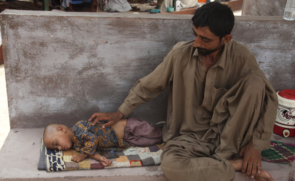 A father waits for medical help for his dehydrated daughter outside a ward at a children’s hospital in Karachi, Pakistan,  on Wednesday.