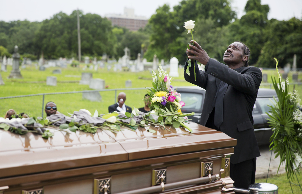 Gary Washington holds up a rose before placing it on the casket of his mother, Ethel Lance, one of the nine people killed in the shooting at Emanuel AME Church last week, after her burial service Thursday in Charleston, S.C. The Associated Press
