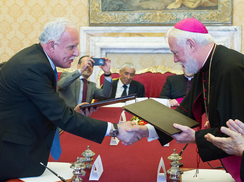 Vatican Foreign Minister Paul Gallagher, right, and his Palestinian counterpart, Riad al-Malki, shake hands after signing a treaty at a ceremony inside the Vatican.
