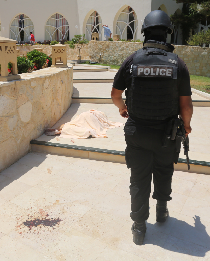 A police officer walks past a covered body near a Tunisian beach, in Sousse on Friday.