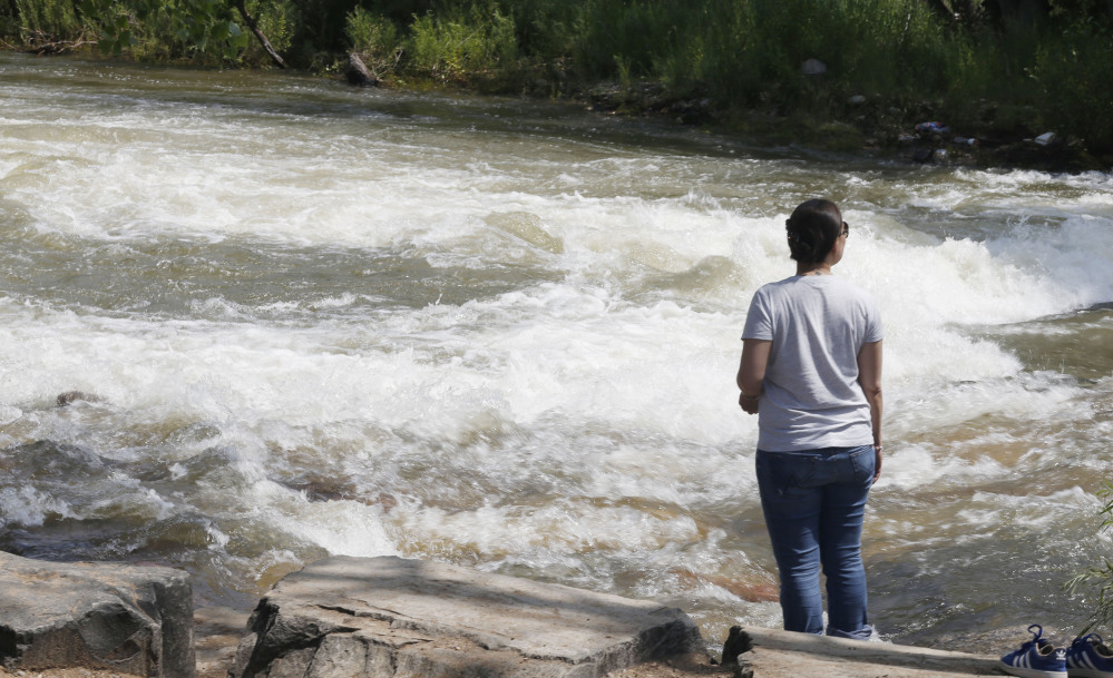 Clear Creek rushes past a woman in Golden, Colo., on Tuesday. Rapidly melting snow is sending Colorado’s rivers racing out of the mountains. Some commercial operations are seeking calmer rapids and stocking extra safety gear.