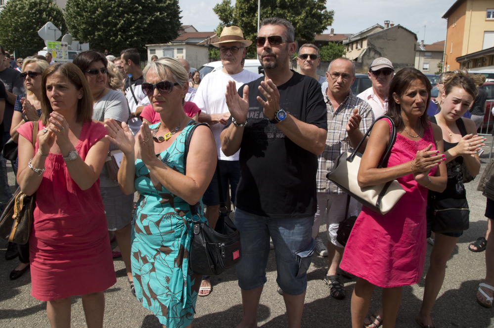 People applaud after a moment of silence in Quentin-Fallavier, southeast of Lyon, France, on Saturday to pay their respects to the victim of the attack that took place Friday.