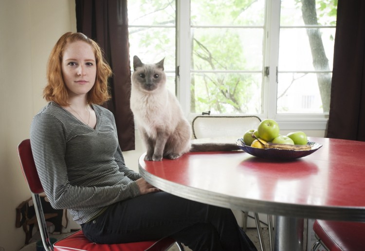 Sarah Fearing, who graduated from the University of Maine in May, says she and her parents prepared for the financial burden of school, but she still wound up with some debt. Sitting with her cat Sam at her home in Brewer, Fearing said her dad deposits bottle-return funds into her bank account to help defray costs.
