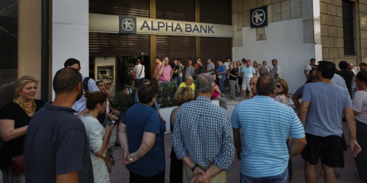 People stand in line Sunday to use a cash machine of a bank in central Athens on Sunday.