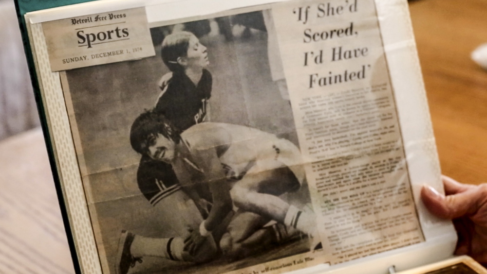 Cyndi Bona holds a news clipping from her time playing basketball at Pratt Institute, where she was the first woman to play men’s NCAA basketball.