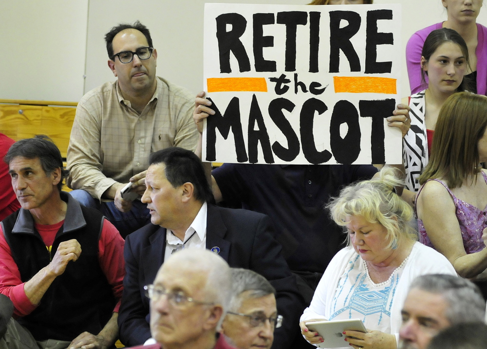 Mark Roman holds a sign calling for the retirement of the Indians nickname for Skowhegan High School sports teams during a forum May 4.