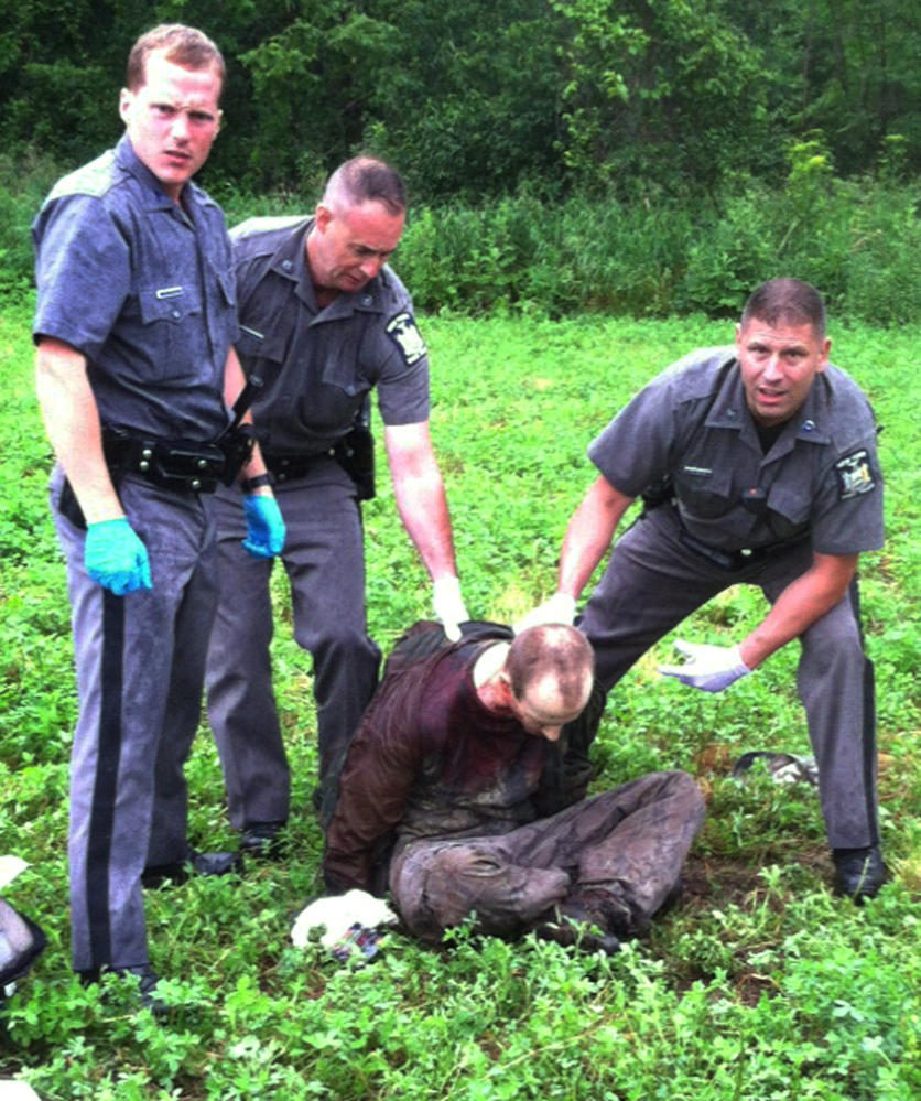 State police stand over David Sweat after he was shot and captured near the Canadian border Sunday in Constable, N.Y. Sweat was hospitalized in critical condition late Sunday. His condition has been upgraded to serious and authorities say he has been talking to police.