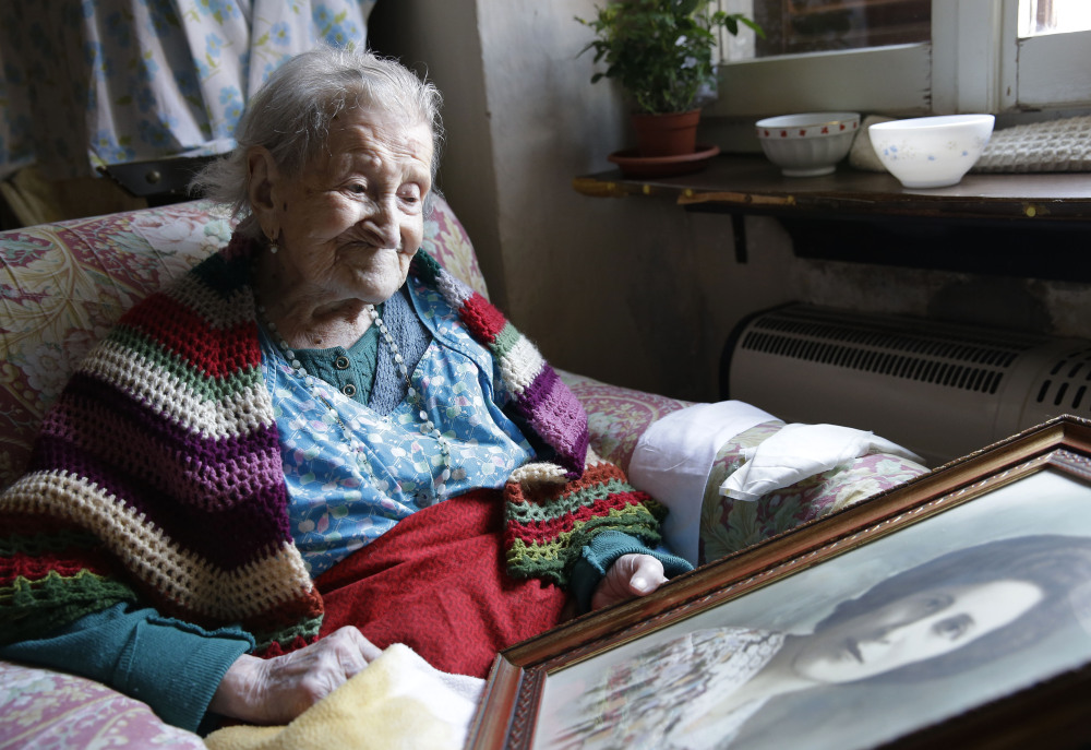 Emma Morano, 115, looks at an old portrait of herself in her apartment in Verbania, Italy.
