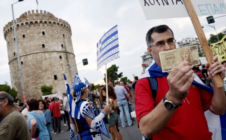 A supporter of voting “no” in the upcoming referendum holds an old 1,000 drachma bank note during a rally in the northern Greek port city of Thessaloniki on Monday. Others fear a return to the drachma would be chaotic.