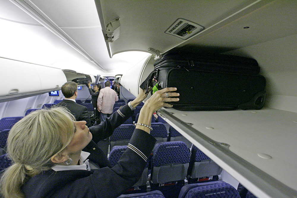 An American Airlines flight attendant loads a bag in the overhead bin of  a Boeing 737-800 jet, at Dallas Fort Worth International Airport in Grapevine, Texas. The Associated Press