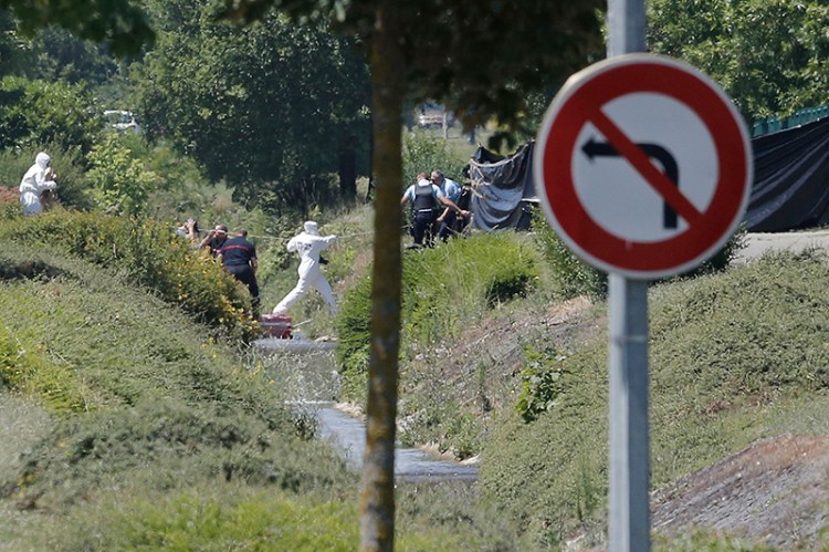 Investigating police officers work outside a gas pant southeast of Lyon, France where a terrorism investigation has been opened after an attack that left one dead and two wounded.