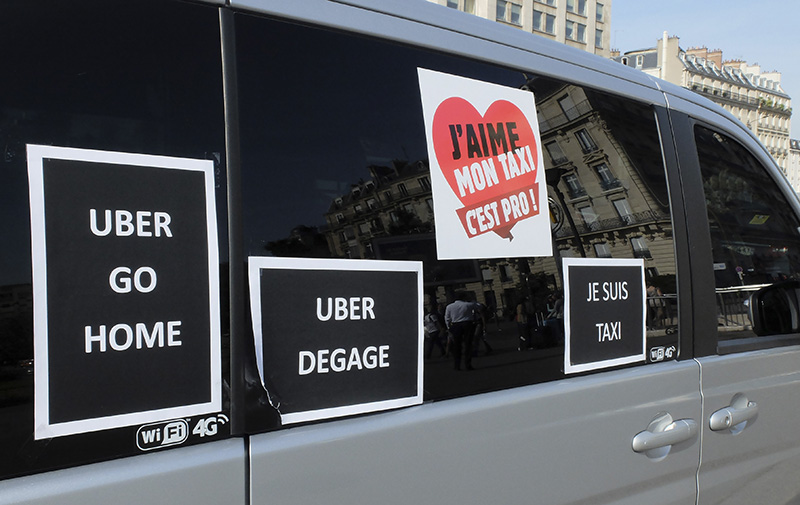 A Paris cab with posters reading " Uber get out", (Uber dégage),  parks during a blockade by taxi drivers in Paris.
