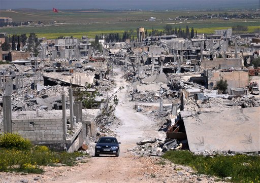In this April 18, 2015, photo a car passes through an area of Kobani that was destroyed during the battle between U.S. backed Kurdish forces and  Islamic State fighters. Turkish officials say the Islamic State group has staged a new attack to retake Kobani. The Associated Press