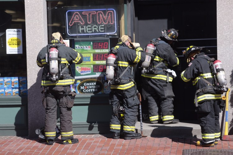 Firefighters don breathing masks to enter a storefront adjacent to Paul's Foods on Congress Street where they were investigating reports of a freon leak. Gabe Souza/Staff Photographer 