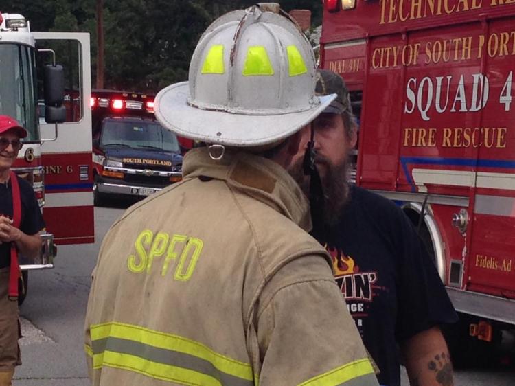 A firefighter talks to a man at the scene of a fire on Burwell Avenue in South Portland. (WCSH photo)