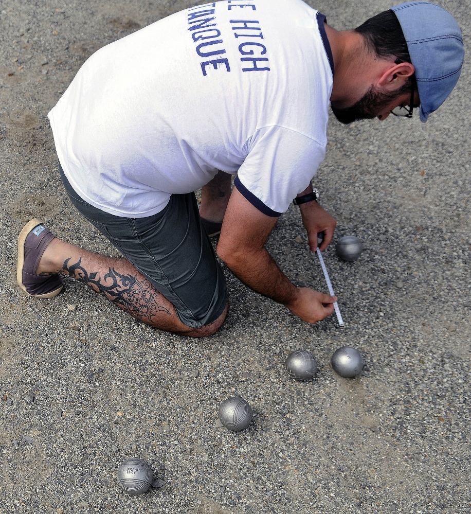 Stephen Lessard of Denver, Colo., measures the distance between petanque balls Sunday during an annual tournament at Mill Park in Augusta.