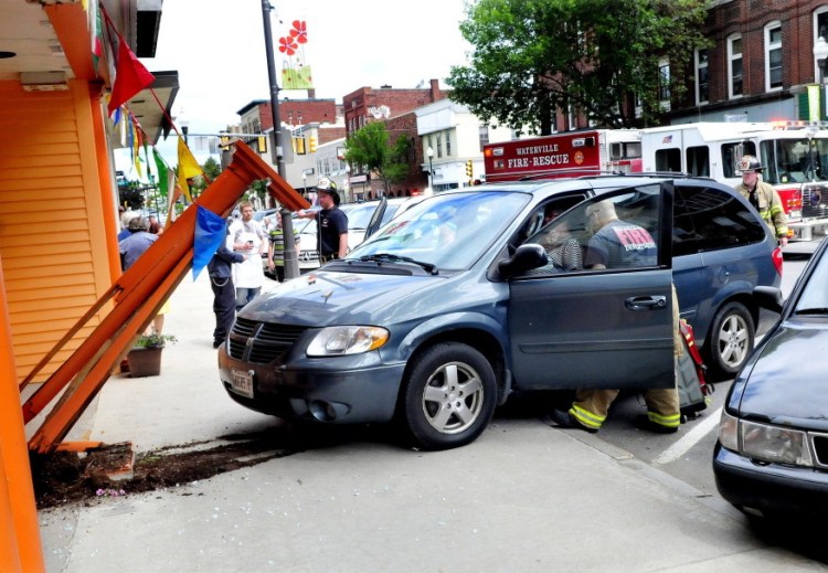Rescue workers treat a female driver of the van that crashed into the front of the Jewel of India Restaurant Thursday morning, smashing a glass entry door and wood structure in front on Main Street in Waterville.
