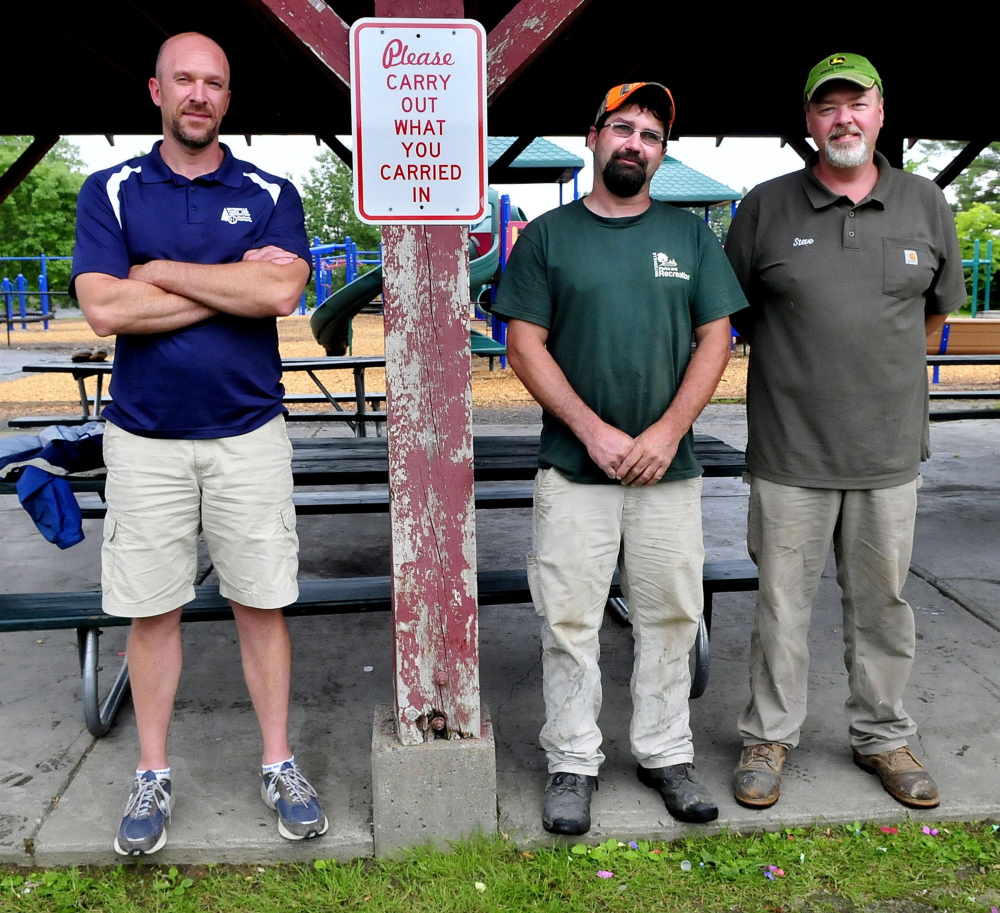 Matt Skehan, left, director of Waterville Parks and Recreation, and employees Sam Green and Steve Buzzell stand beside a sign urging users to remove their trash at the North Street playground and other city parks in Waterville.