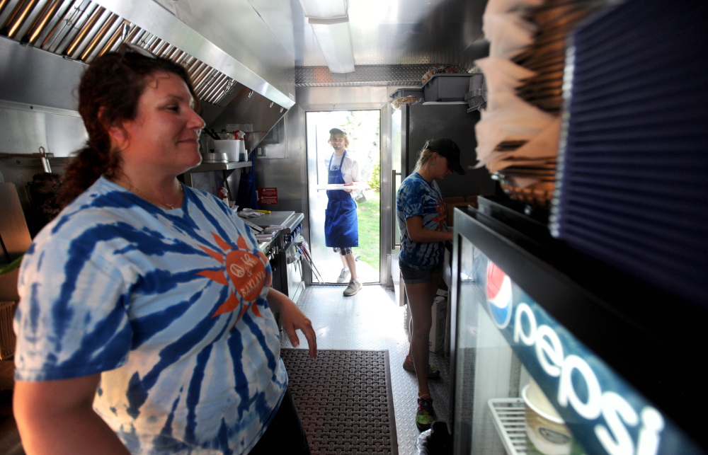 Dom Dexter enters the Spiro and Co. food truck on Thursday as owner Lori Yotides, left, and Taylor Lenentine, right, prepare food at 78 Main St. in Belgrade.