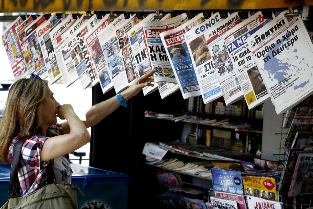 A woman scans Greek newspapers for information on Sunday's referendum. Greece braced for more chaos on the streets Thursday, as Athens and its creditors halted talks on resolving the country's deepening financial crisis until a referendum this weekend. The Associated Press