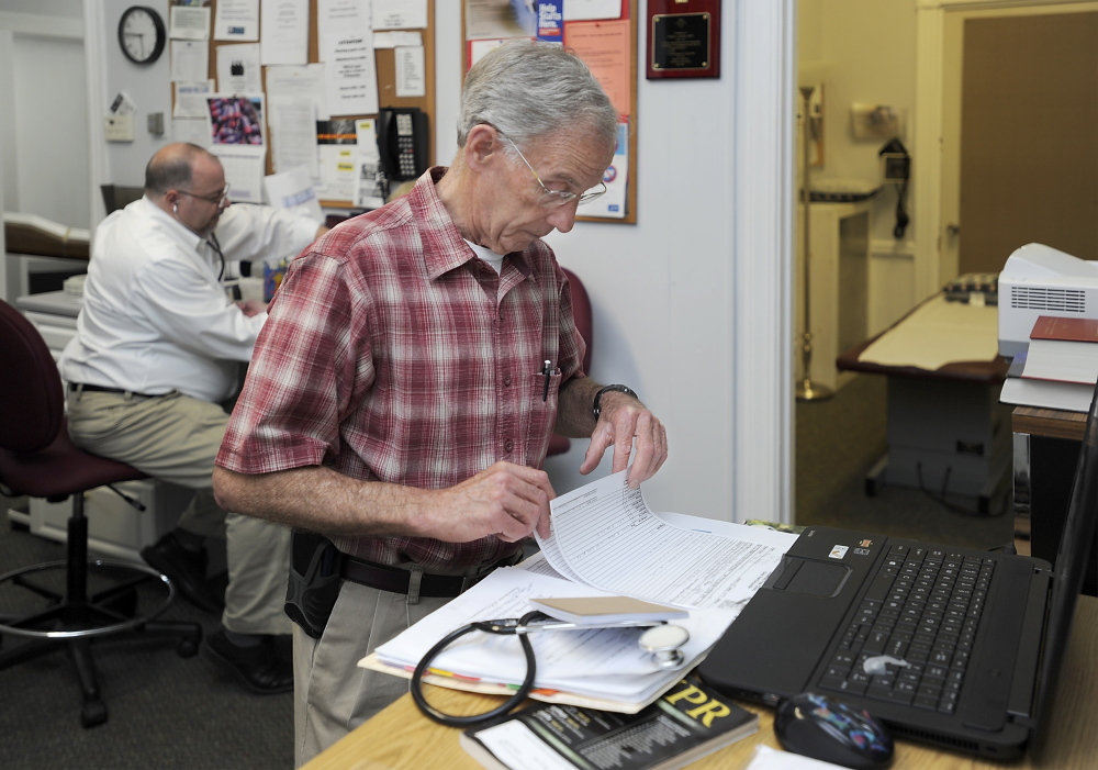 Dr. Frank Kleeman, founder of the Biddeford Free Clinic, goes over paperwork as he prepares for the clinic’s closure in September after 22 years.