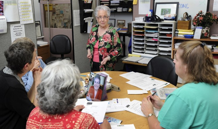 Joan Gordon, center, executive director of the Biddeford Free Clinic, helps volunteers fill out paperwork for clients to get health insurance. “I know it’s time to go, but it’s hard,” she admits.