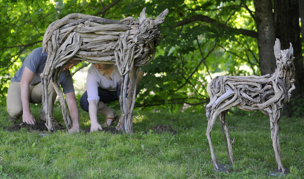 Benjamin Stoodley and Arielle Cousens install their sculpture “Navi” on the Vaughan Homestead lawn Friday as part of the Hallowell property’s summer sculpture garden.