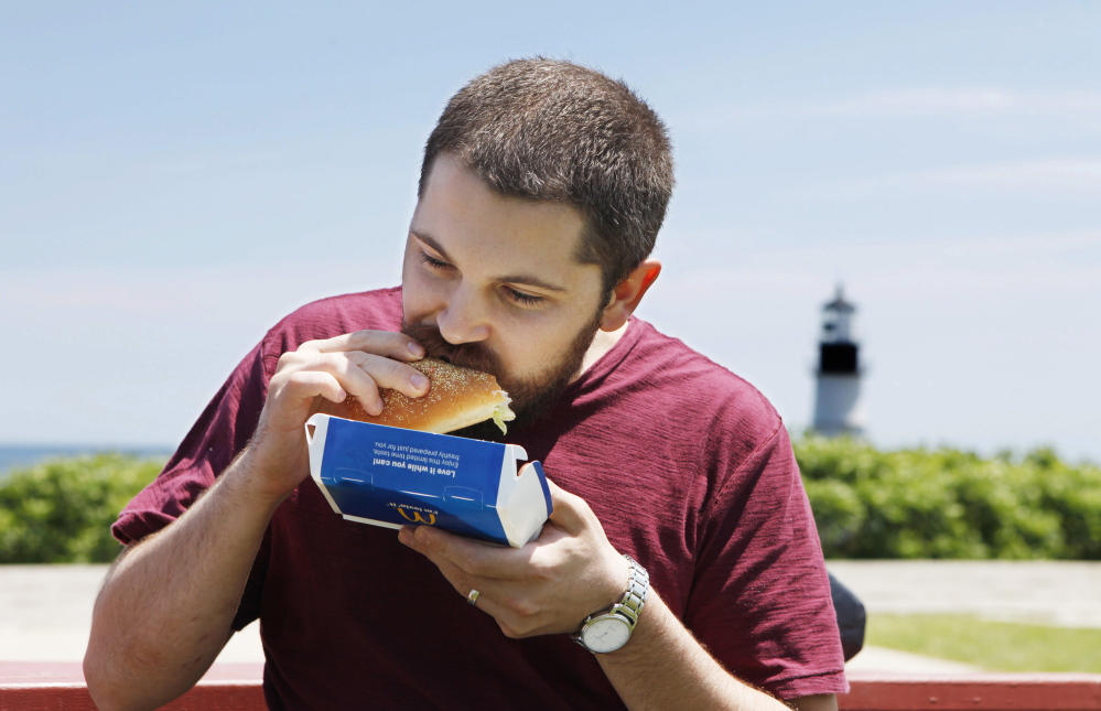Matt Smith samples a McDonald's lobster roll Thursday at Fort Williams Park in Cape Elizabeth.
 Joel Page/Staff Photographer